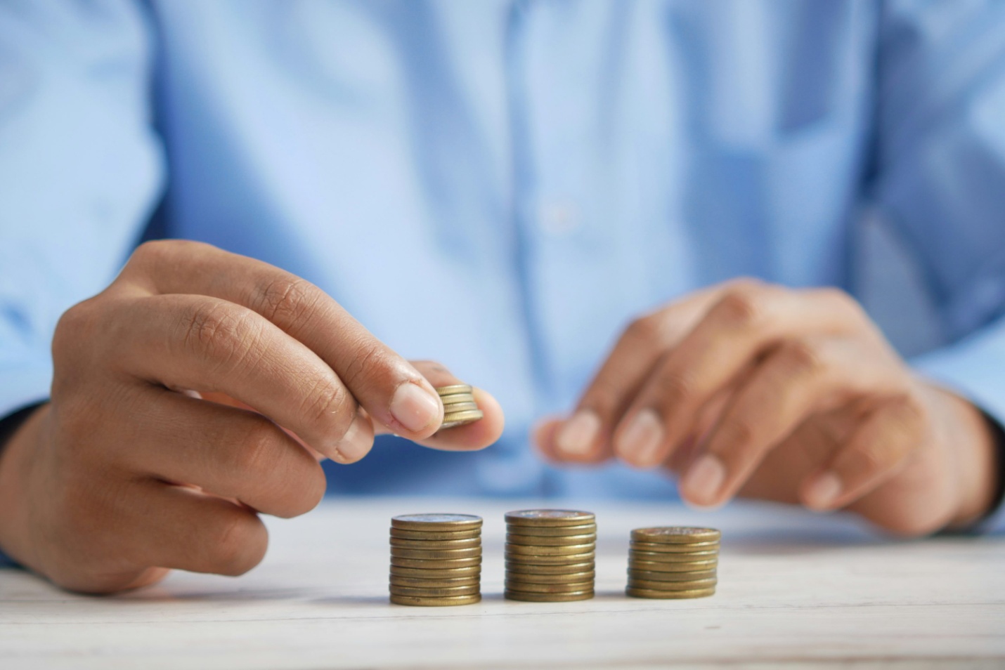 A man counting and stacking coins on a table 