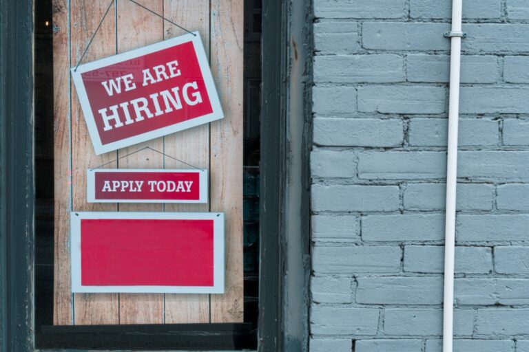 A sign for hiring hanging on a wall