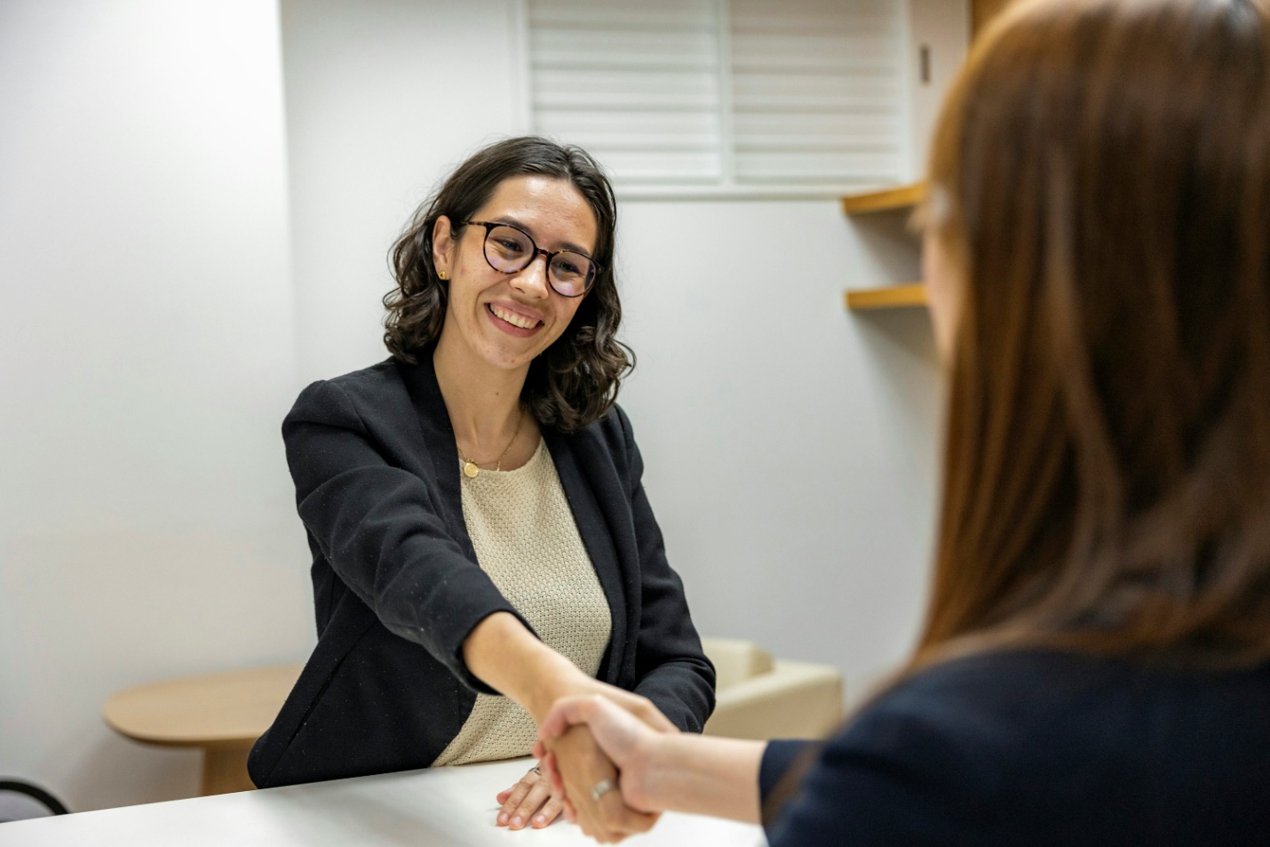 Two women shaking hands in a workplace